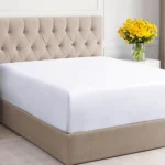 An extended twin bedsheet with perimeter elastic to maintain shape and tension through commercial laundry cycles