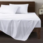 White cotton flat sheets installed in a commercial guest room