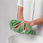 A guest drying hands with a plush green luxury face towel